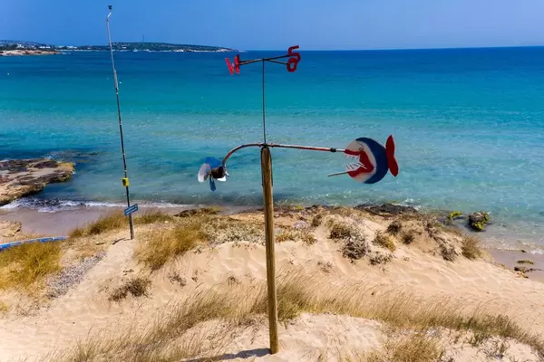Windspiel mit Himmelsrichtungsanzeige, im weißen Sandstrand vor dem weiten Meer in der Ägäis