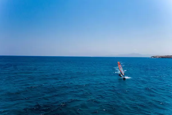 Windsurfer on the deep blue sea, in front of the Santa Maria beach of Paros, Greece