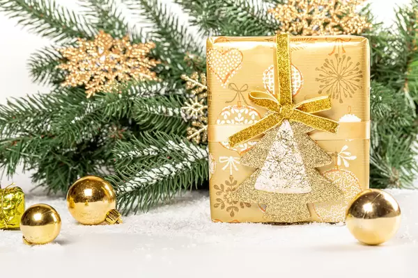 Winter holidays background with golden gift, branches and balls