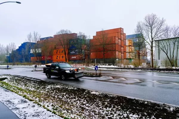 Winter service vehicle driving past the shipping containers storage in Hamburg’s port