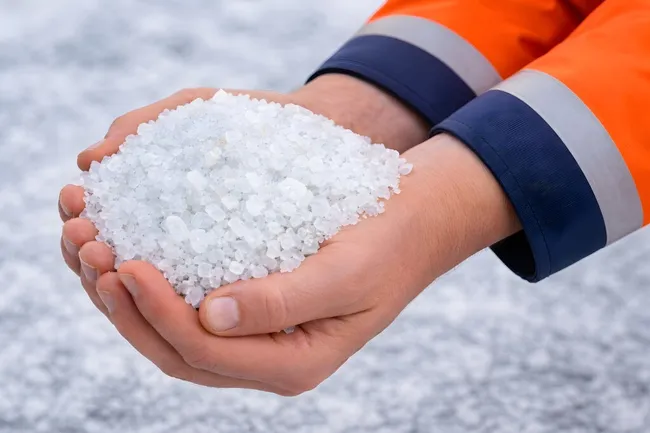Winterdienst bei Schneefall: Salzstreuer in Mitarbeiterhand
