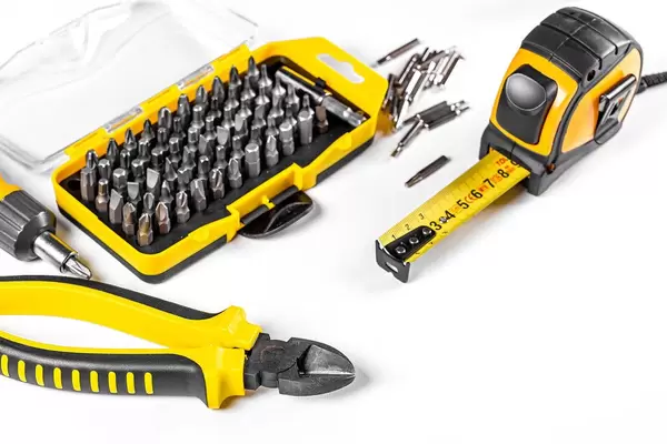 Wire cutters, set of bits, tape measure and screwdriver on white