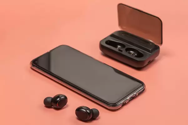 Wireless headphones and smartphone on pink background