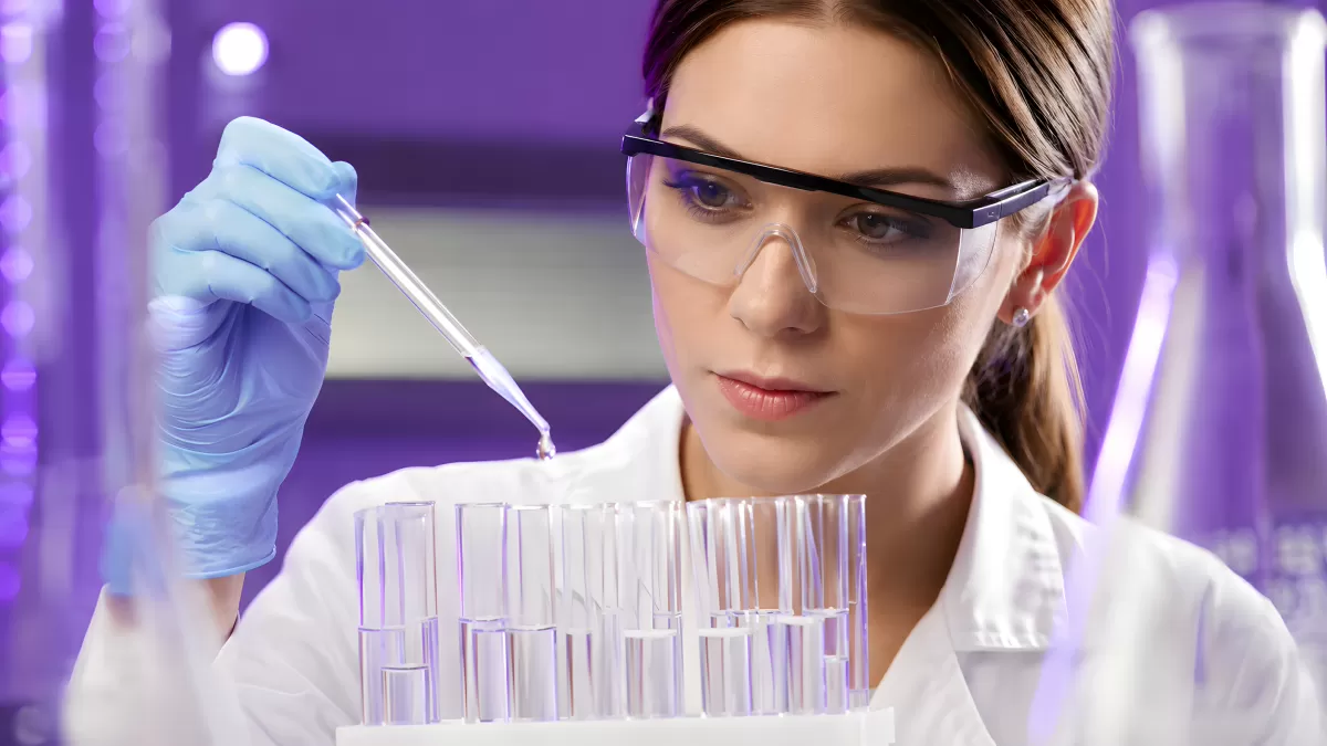 Wissenschaftlerin pipettiert in Reagenzgläser im Labor