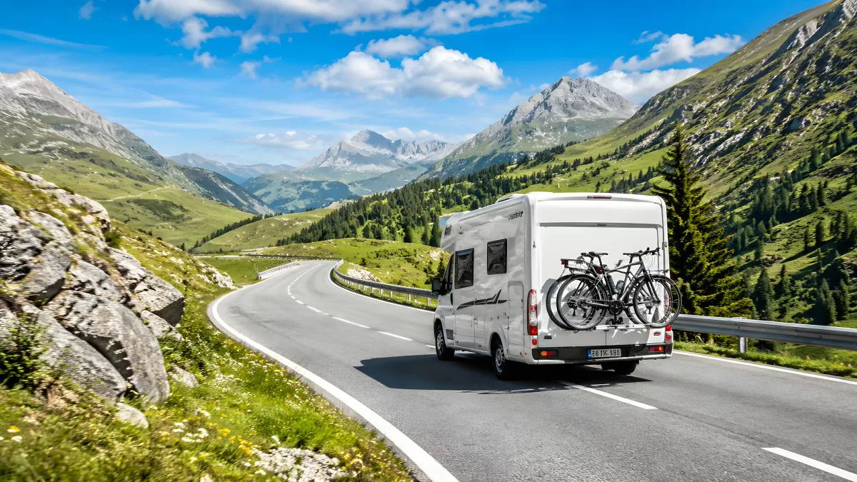Wohnmobil auf Alpenstraße mit Fahrrädern am Heck — Bild kostenlos herunterladen