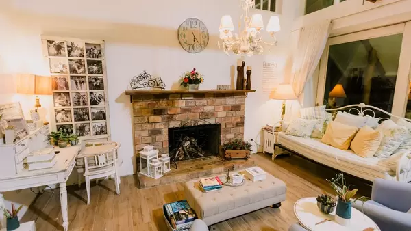 Wohnzimmer eines privaten Gästehauses mit offenem Kamin und heller, rustikaler Einrichtung