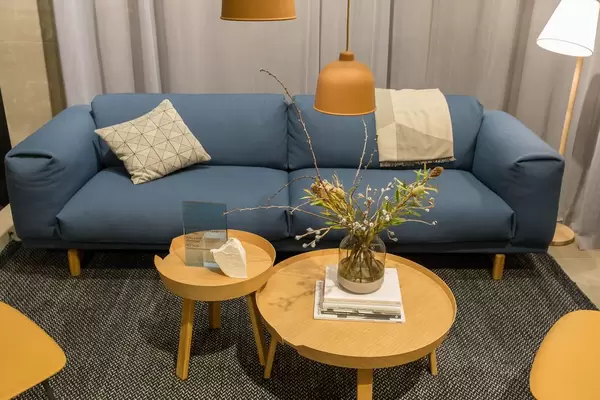 Wohnzimmerkonzept - weiches, gemütliches Sofa mit Zierkissen und runde, hölzerne Beistelltischen