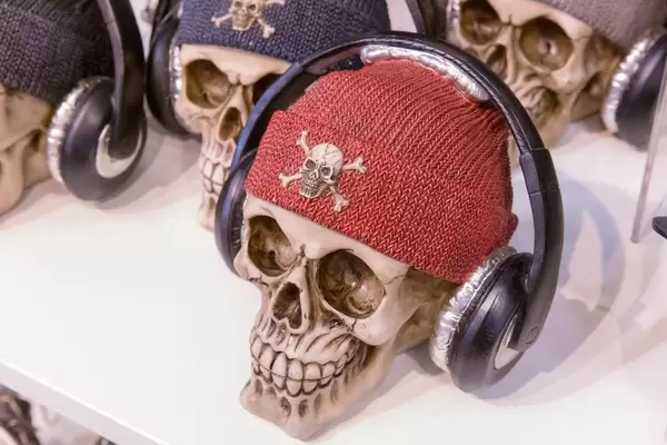 Wollmütze mit Totenkopf Schädel verziert auf einem Totenkopf Schädel mit Kopfhörern