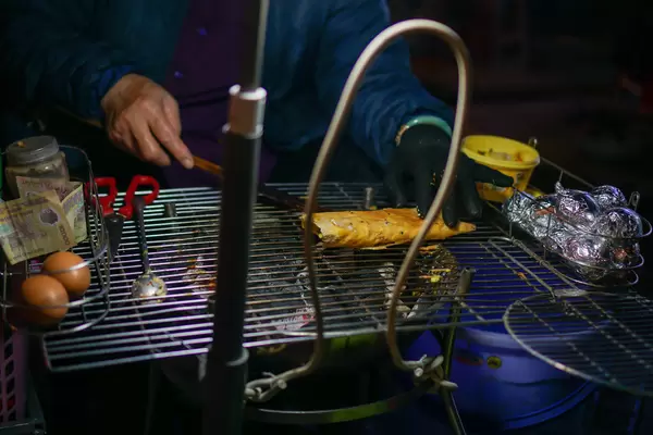 Woman at a Street Food Vendor preparing Vietnamese Pizza called Banh Trang Nuong on a Barbecue Grill