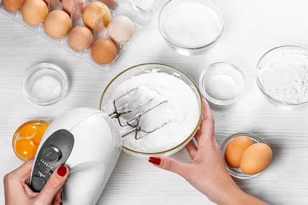 Woman beats egg whites with a mixer. Top view of the process of making a pie (Flip 2019)