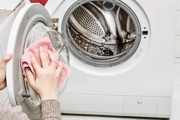 Woman cleaning washing machine with a wipe