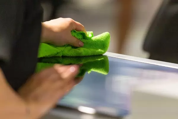 Woman cleans the kitchen surface with a green, dry cloth