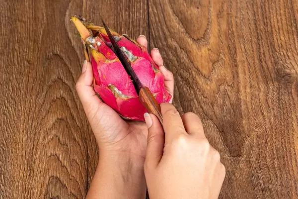 Woman cuts a pitahaya fruit with a knife