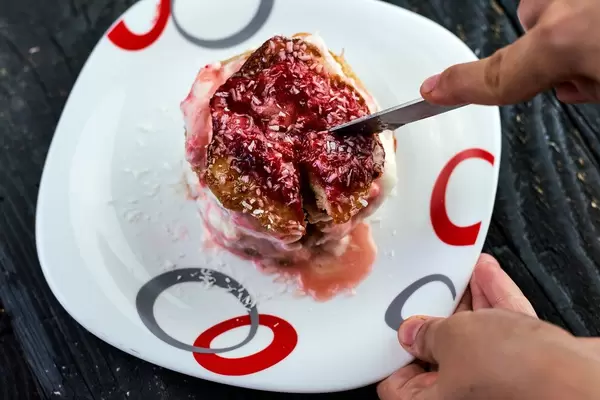 Woman cutting a delicious oatmeal cake with fruit filling