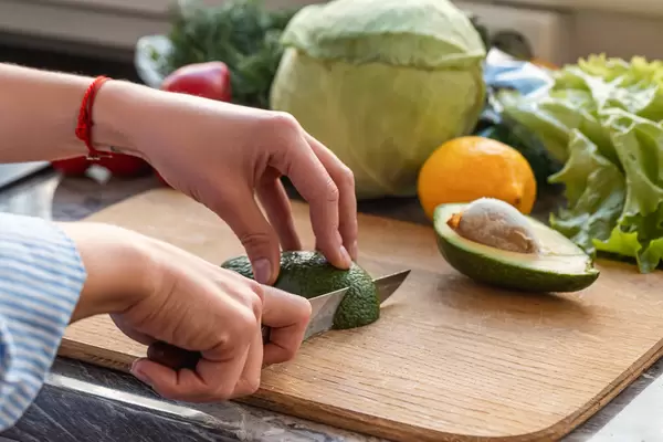 Woman cutting fresh avocado at table. Breakfast of avocado