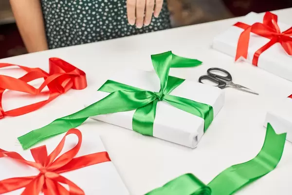 Woman decorating Xmas present with colorful ribbons