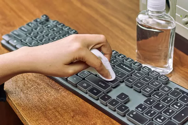 Woman disinfecting a pc keyboard