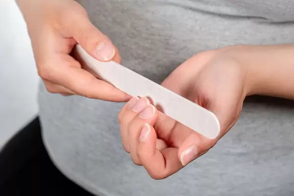 Woman does manicure herself using a nail file