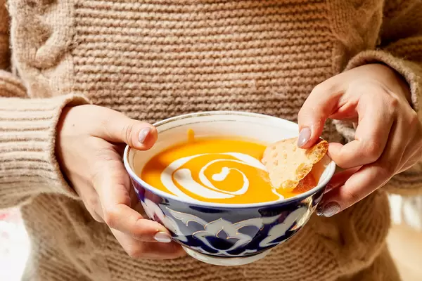 Woman eating tasty cream soup at home
