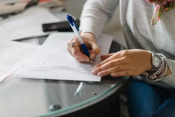 Woman fills out forms on a glass table