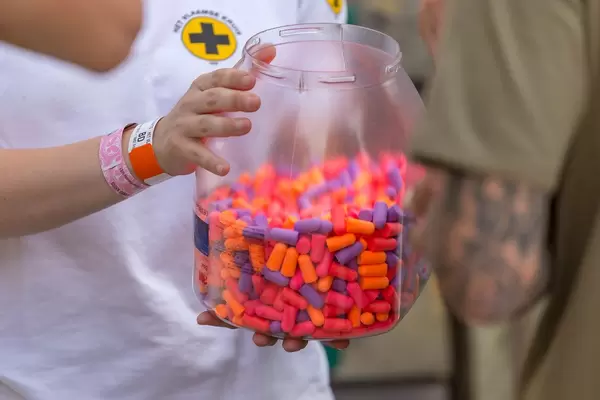 Woman from the first aid team offers colorful ear plugs from a big plastic jar to the visitors of Tomorrowland