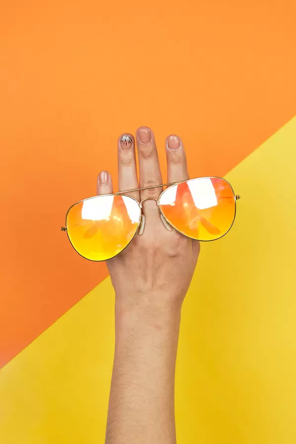 Woman hand holding bright sunglasses