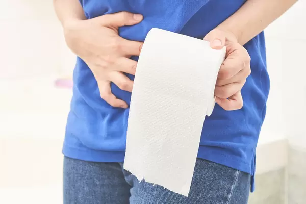 Woman hand holding her abdomen and toilet paper roll