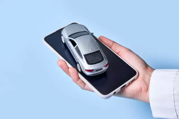 Woman hand holds smartphone and car toy. Concept of car sharing, calling taxi or delivery