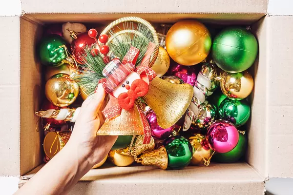 Woman hand takes out Christmas decorations from box