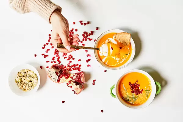 Woman hand with spoon tasting fresh homemade creamy soup