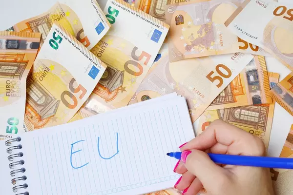 Woman hand writing EU, 50 Euro banknotes background