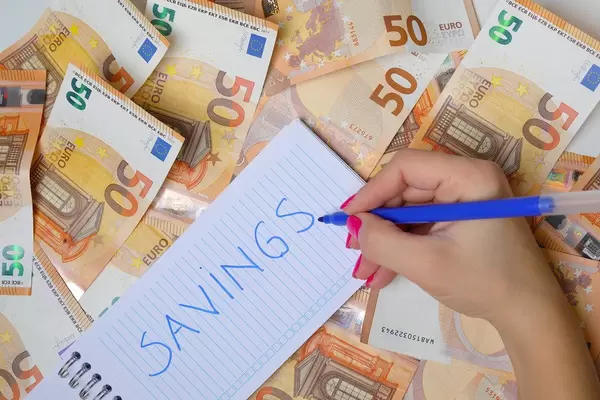 Woman hand writing Savings, 50 Euro banknotes background