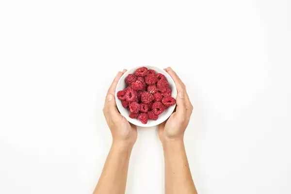 Woman hands holding a bowl of freshly picked raspberries