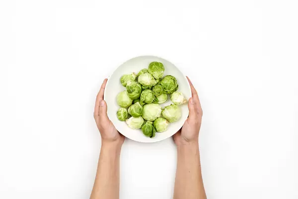 Woman hands holding a bowl of tiny cabbages also called Brussels sprouts