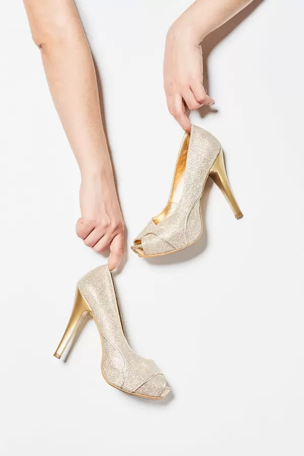 Woman hands holding a pair of high heel shoes over white background