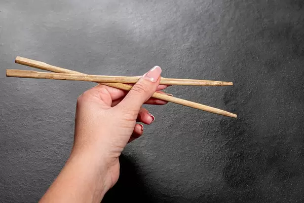 Woman hands holding chopsticks on black background