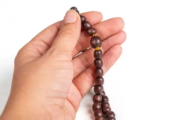 Woman hands holding rosary on white background