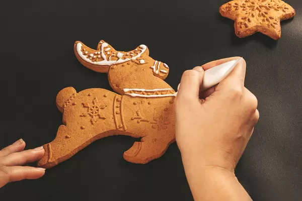 Woman hands paint a xmas treats, ornaments. Christmas preparations