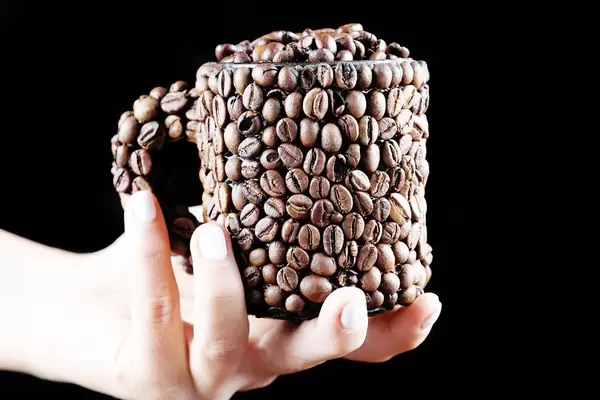 Woman holding a cup of coffee beans in her hand, black background (Flip 2019)