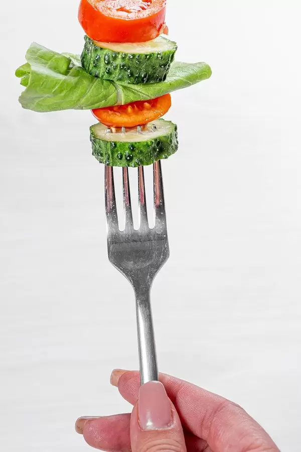 Woman holding a fork with fresh vegetables. Healthy eating concept (Flip 2019)
