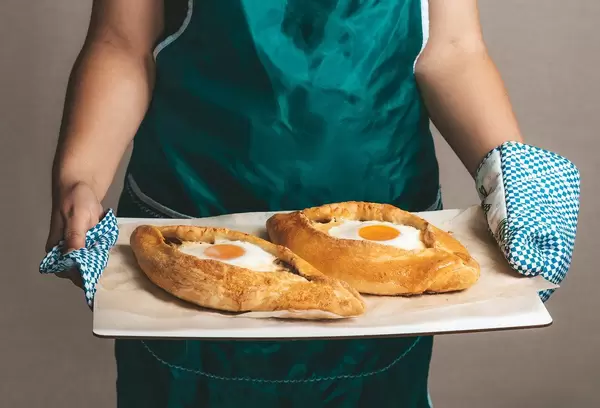 Woman holding hot baked Adjarian khachapuri in her hands