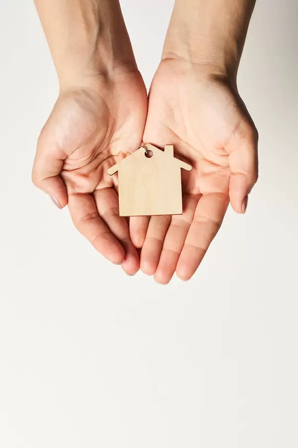 Woman holding wooden figure of house