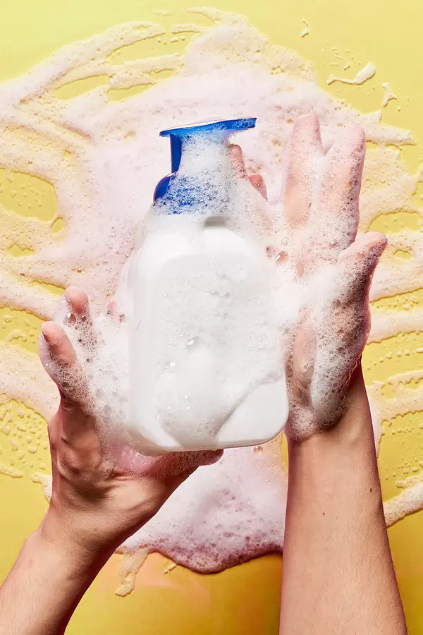 Woman holds a bottle of foaming cream cleanser