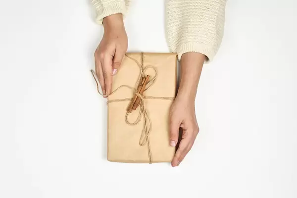 Woman holds handmade Xmas gift wrapped with craft paper