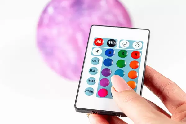 Woman holds in hand a remote control on the background of the sconce planet (Flip 2019)