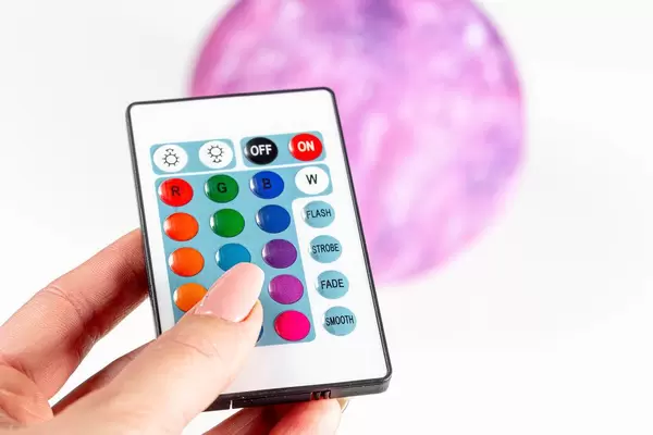 Woman holds in hand a remote control on the background of the sconce planet