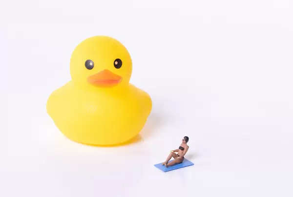 Woman in bathing suit with yellow rubber duck on white background