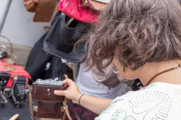 Woman inspecting second-hand cameras at the Naschmarkt flea market in Vienna