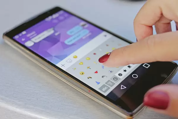 Woman is typing emojis in a chat of her smartphone close up