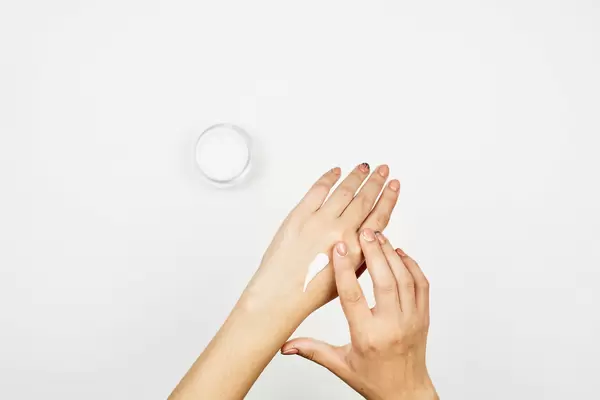 Woman moisturizing her hand with cosmetic cream